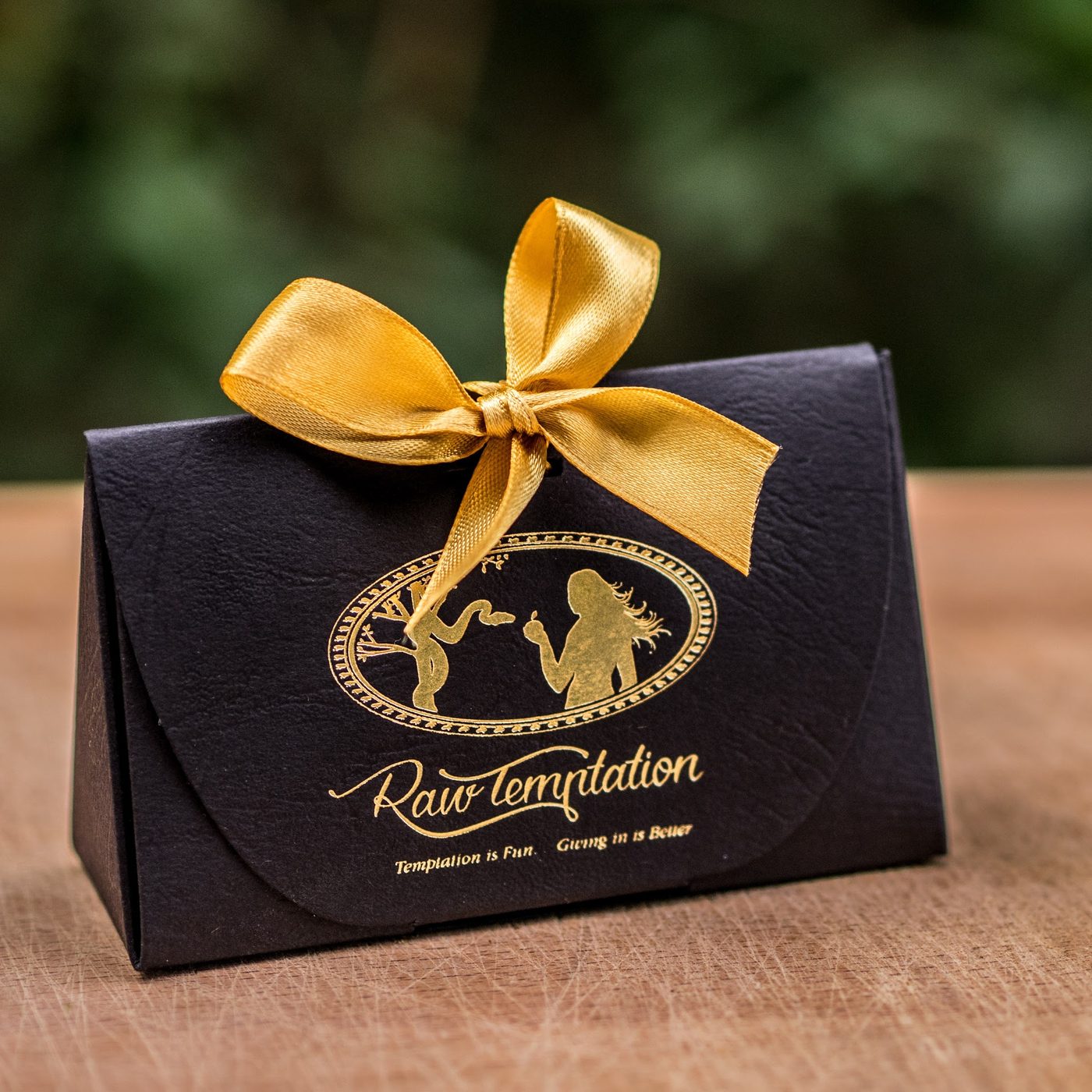 A Raw Temptation gift box tied with a gold bow
